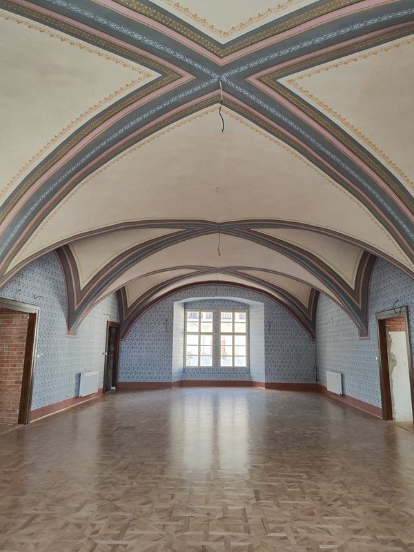 Týž sál po restaurování: barevná žebra kleneb, šablonová malba stěn a parketová podlaha