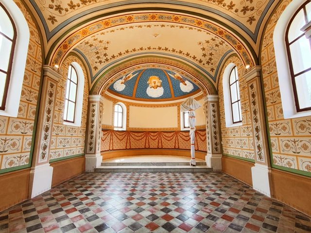 Loď kaple po restaurování: malované klenby a stěny s šablonovou malbou, v presbytáři modrá malovaná klenba a červená malovaná draperie, kachlová podlaha